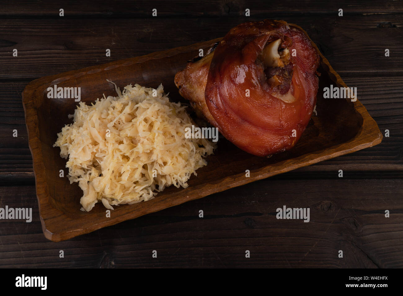 Pork knuckle with sauerkraut on a wooden plate. Oktoberfest. rustic