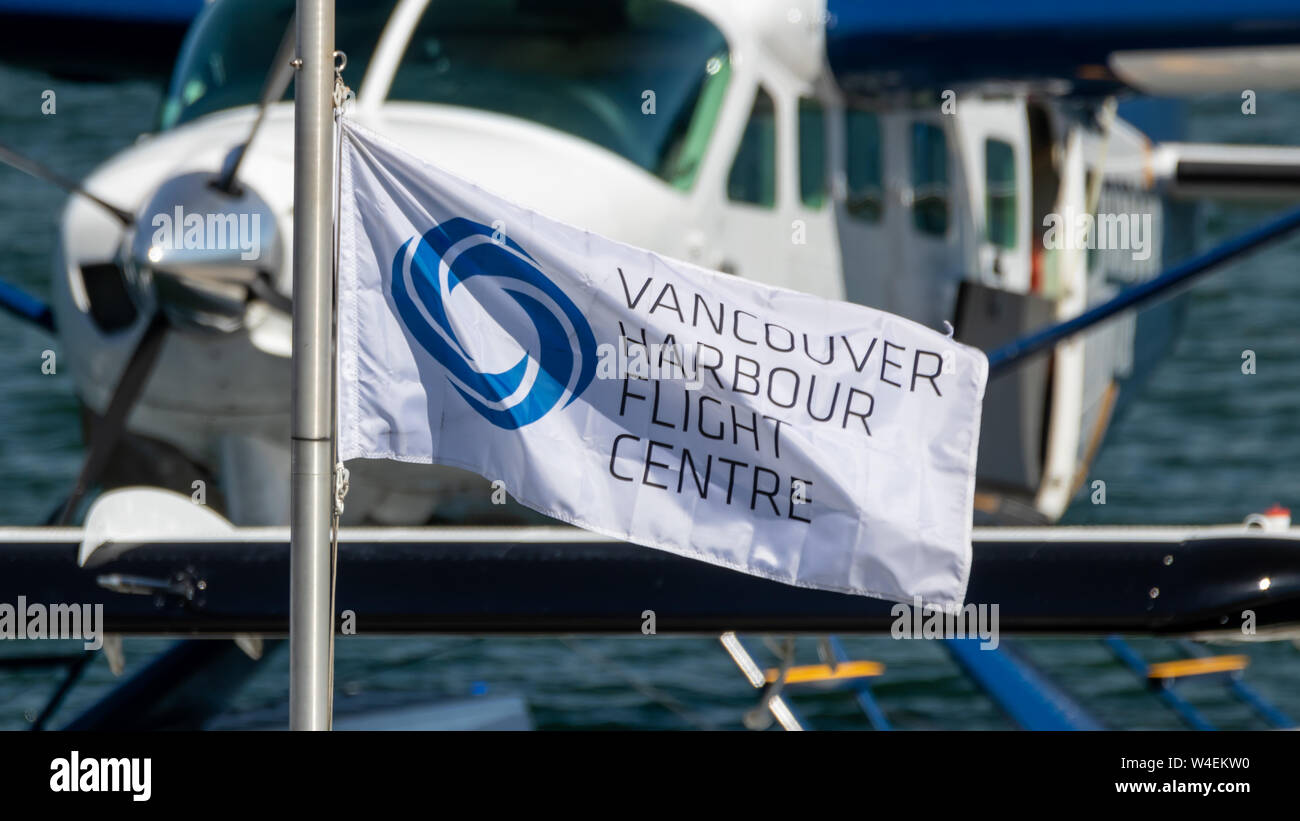 Waving Vancouver Harbour Flight Centre flag in-front of docked seaplane. Stock Photo