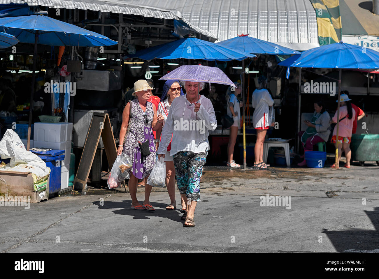 Man using an umbrella as a sunshade and sun protection aid against the extreme tropical sun in Thailand Southeast Asia Stock Photo