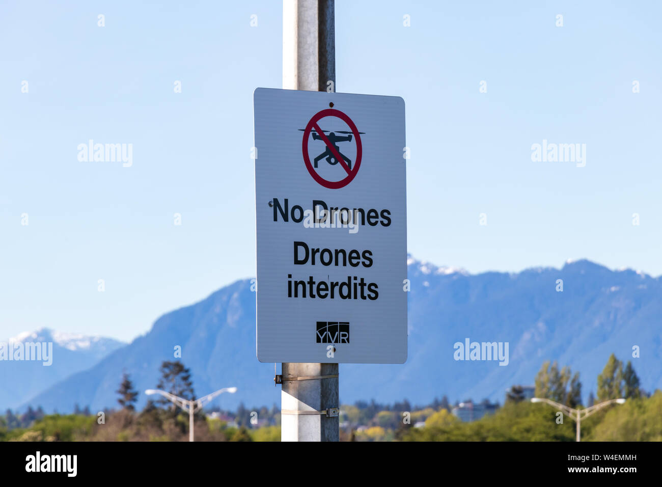 No Drones warning sign on the outskirts of Vancouver International Airport with mountains in the background. Stock Photo