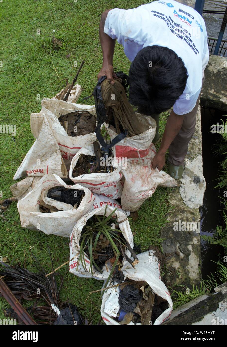 Bogor, West Java, Indonesia - July 2019 : A man put neighborhood trash in a plastic sack. Stock Photo
