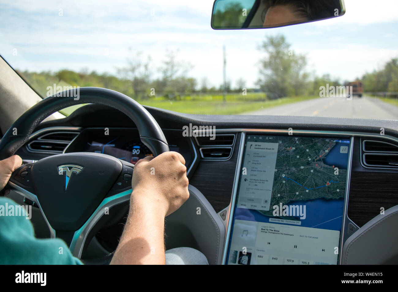 Man Driving Tesla Model S With Navigation On Screen Beside