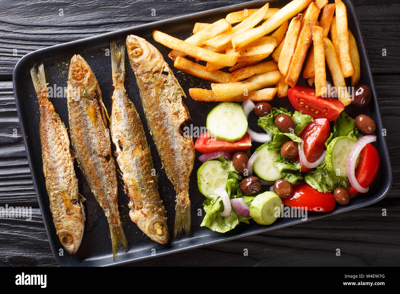 Fried Mediterranean Boops boops fish served with fresh salad and french fries close-up on a plate on the table. horizontal top view from above Stock Photo
