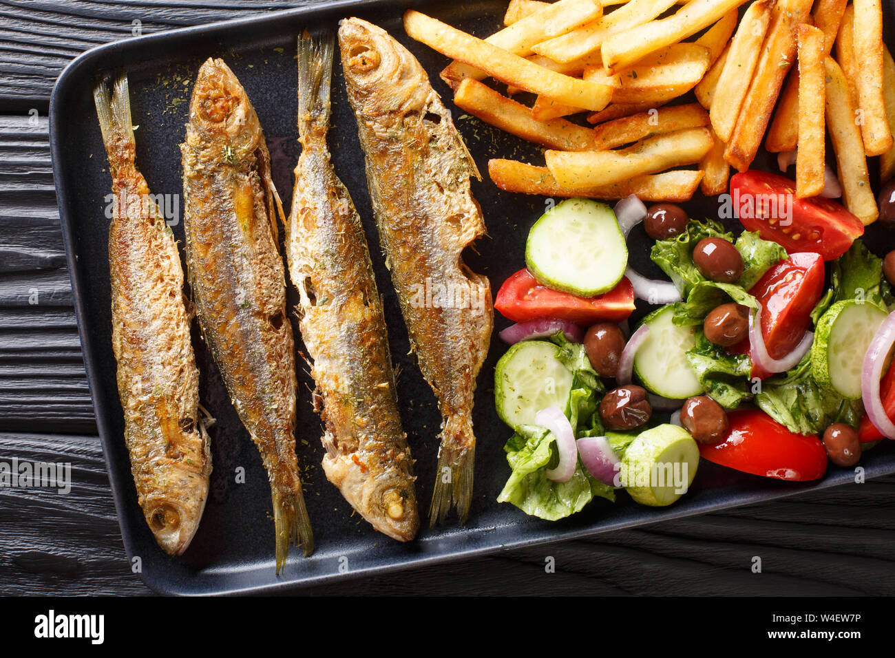 Fried boops boops fish with fresh vegetable salad and french fries close-up on a plate on the table. horizontal top view from above Stock Photo
