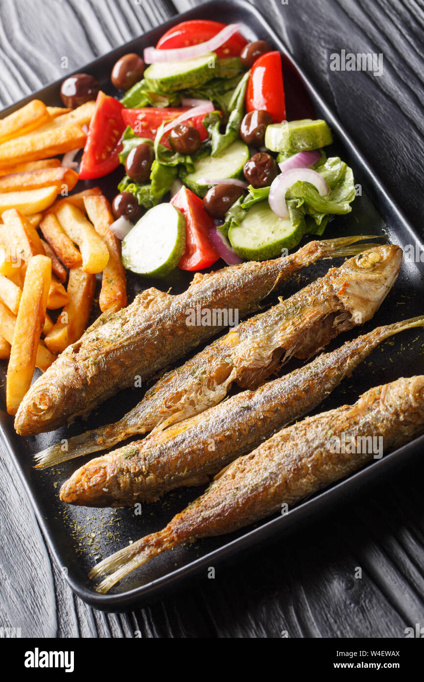 Fried Mediterranean Boops boops fish served with fresh salad and french fries close-up on a plate on the table. vertical Stock Photo