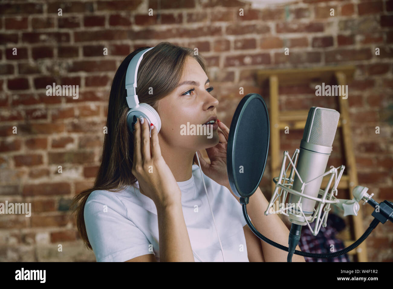 Woman in headphones recording music video blog home lesson, singing or  making broadcast internet tutorial while sitting in loft workplace or at  home. Concept of hobby, music, art and creation Stock Photo -