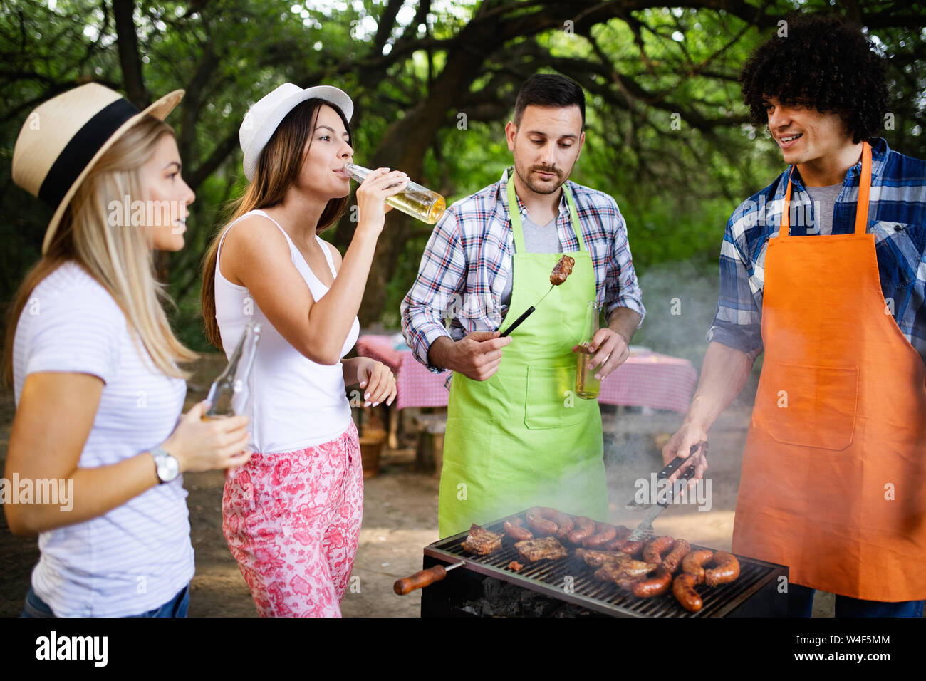 Group of happy friends eating and drinking beers at barbecue dinner