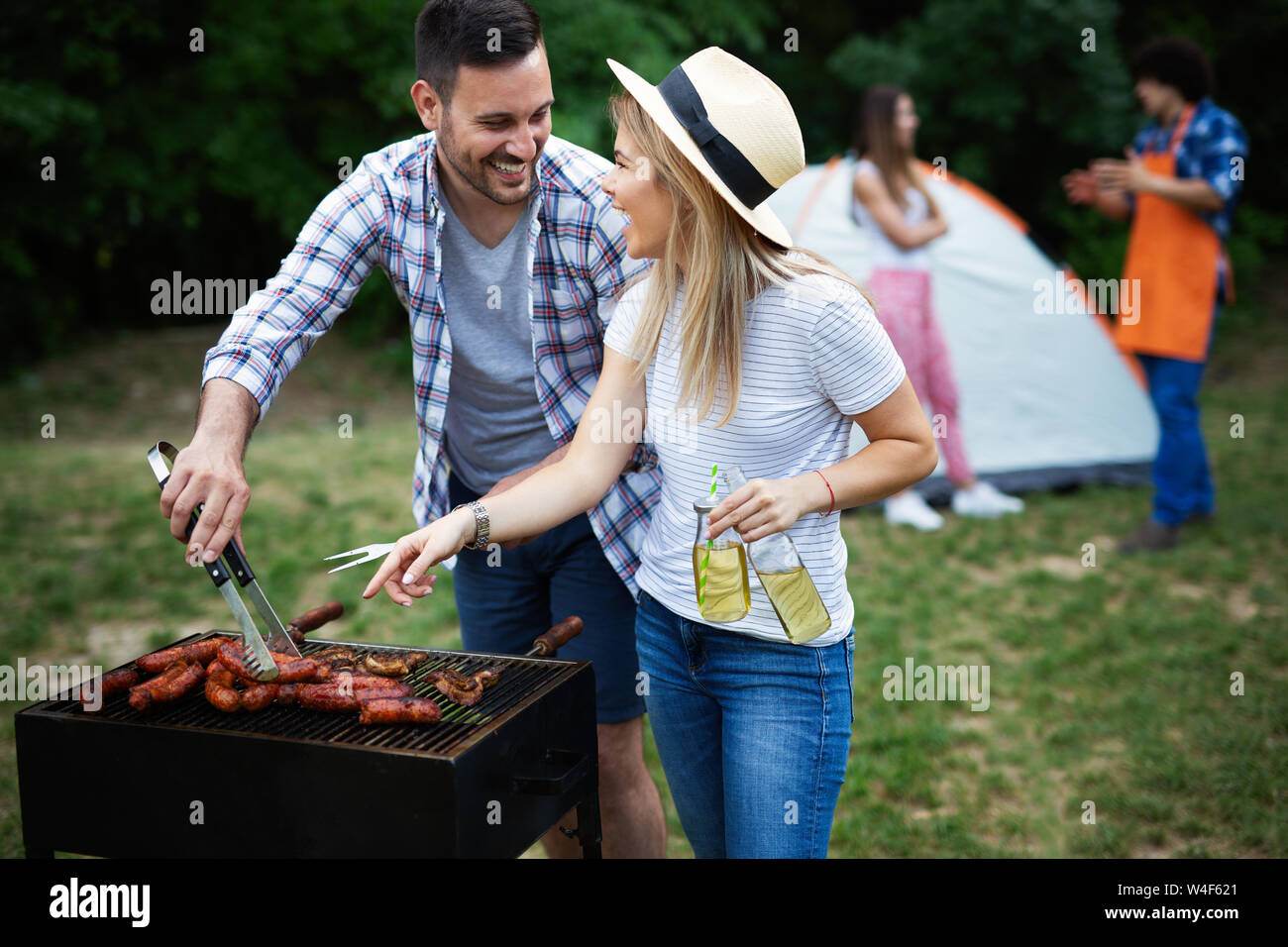 Group of happy friends eating and drinking beers at barbecue dinner