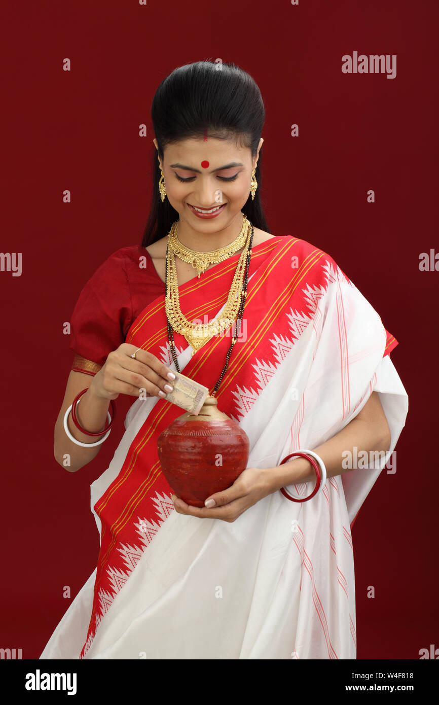 Bengali woman inserting a banknote into a piggy bank Stock Photo Alamy