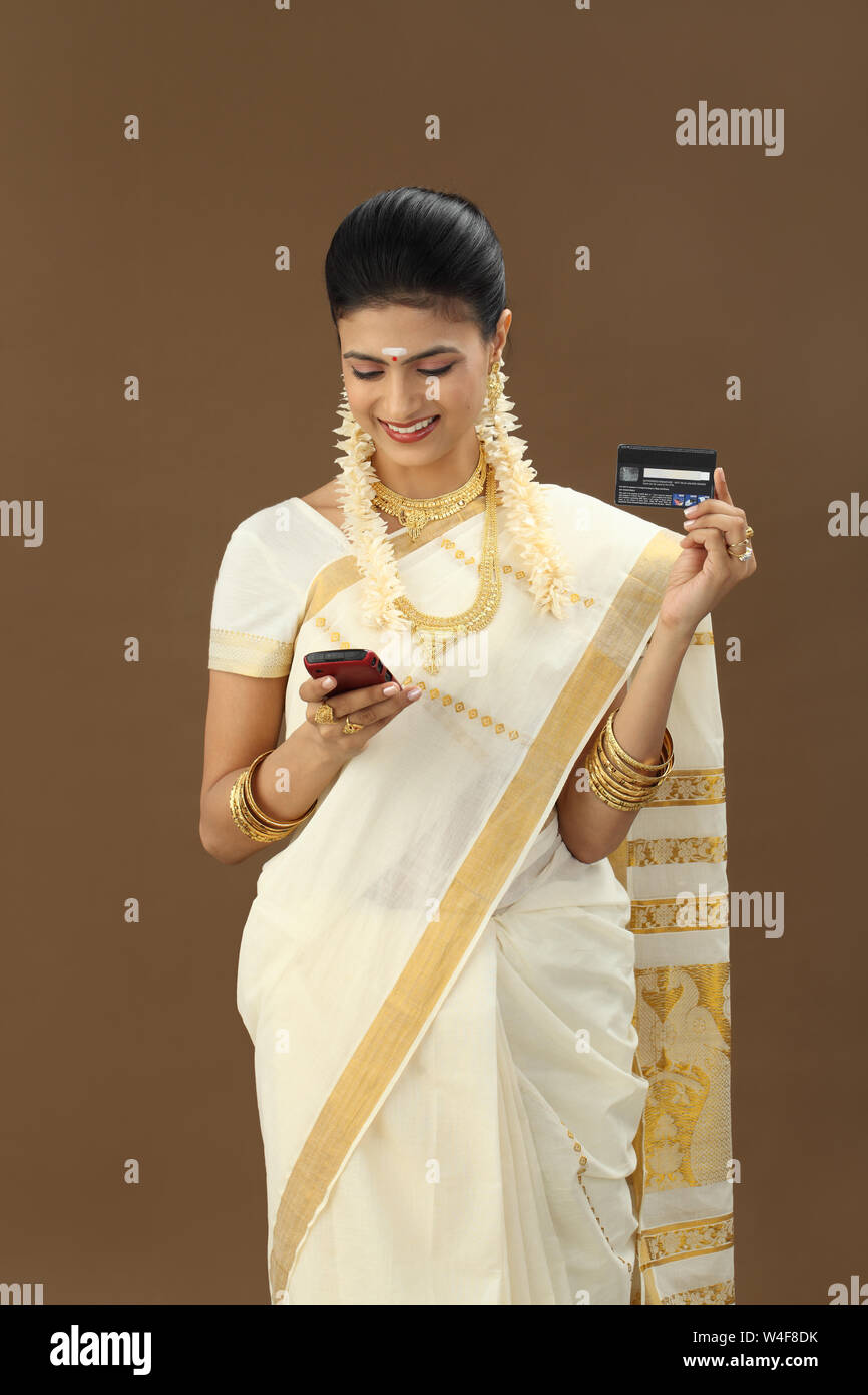 South Indian woman text messaging and holding credit card Stock Photo ...