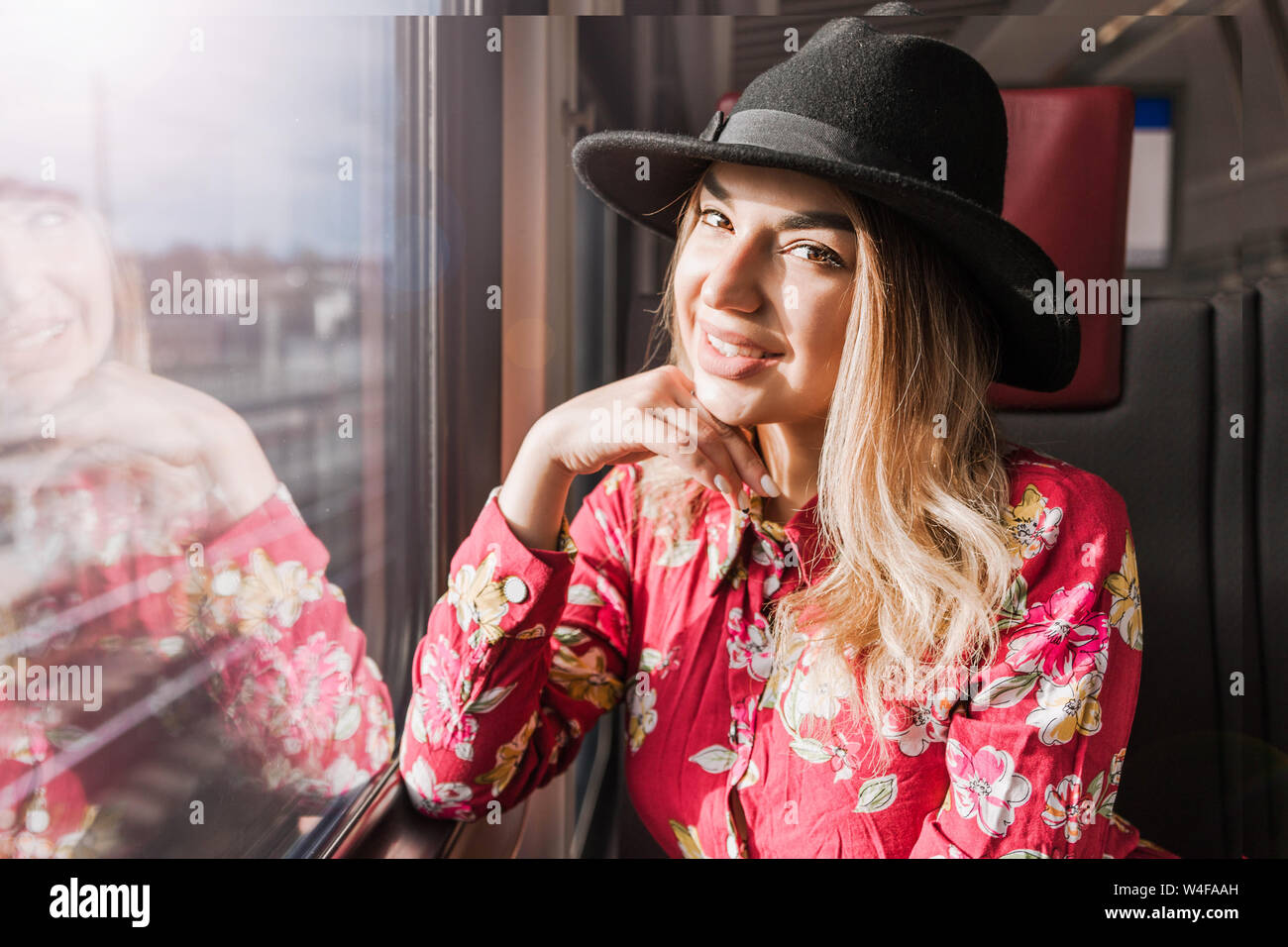 Photo of Beautiful girl sitting alone in the train and looking out the window merrily Stock Photo
