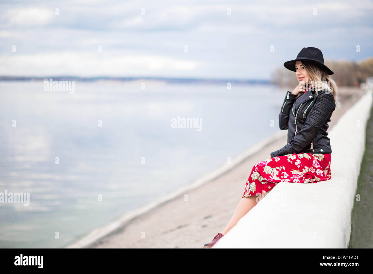 Photo of Beautiful girl in a red dress and black hat sits on the ...