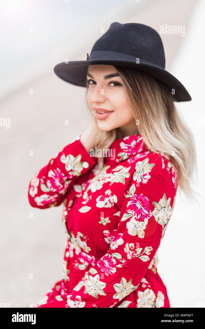 photo of Beautiful girl in red dress and black hat poses for the camera ...