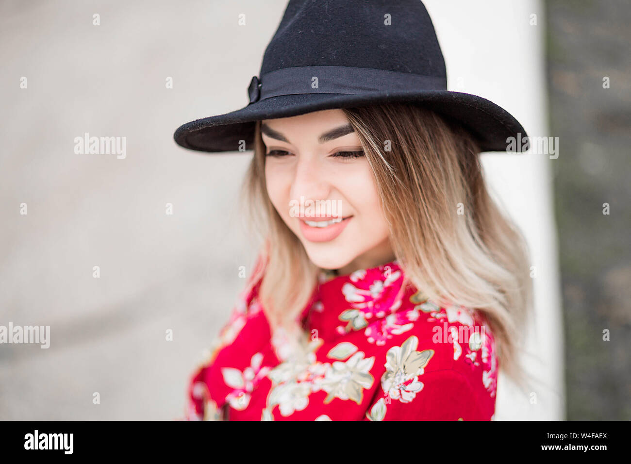 photo of Beautiful girl in red dress and black hat poses for the camera ...
