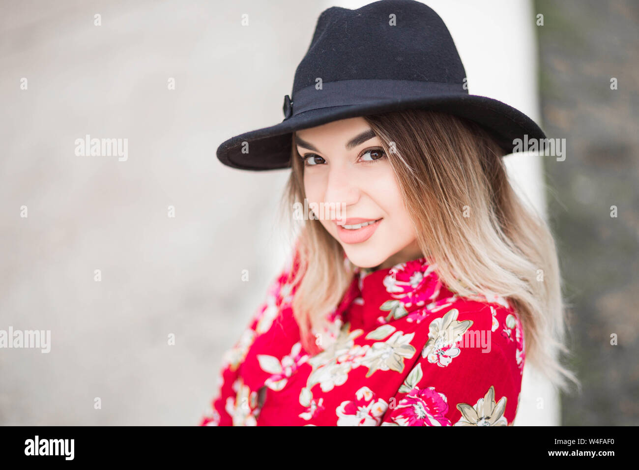 photo of Beautiful girl in red dress and black hat poses for the camera ...