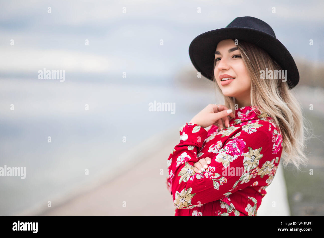 Photo of Beautiful girl in a red dress and black hat sits on the ...