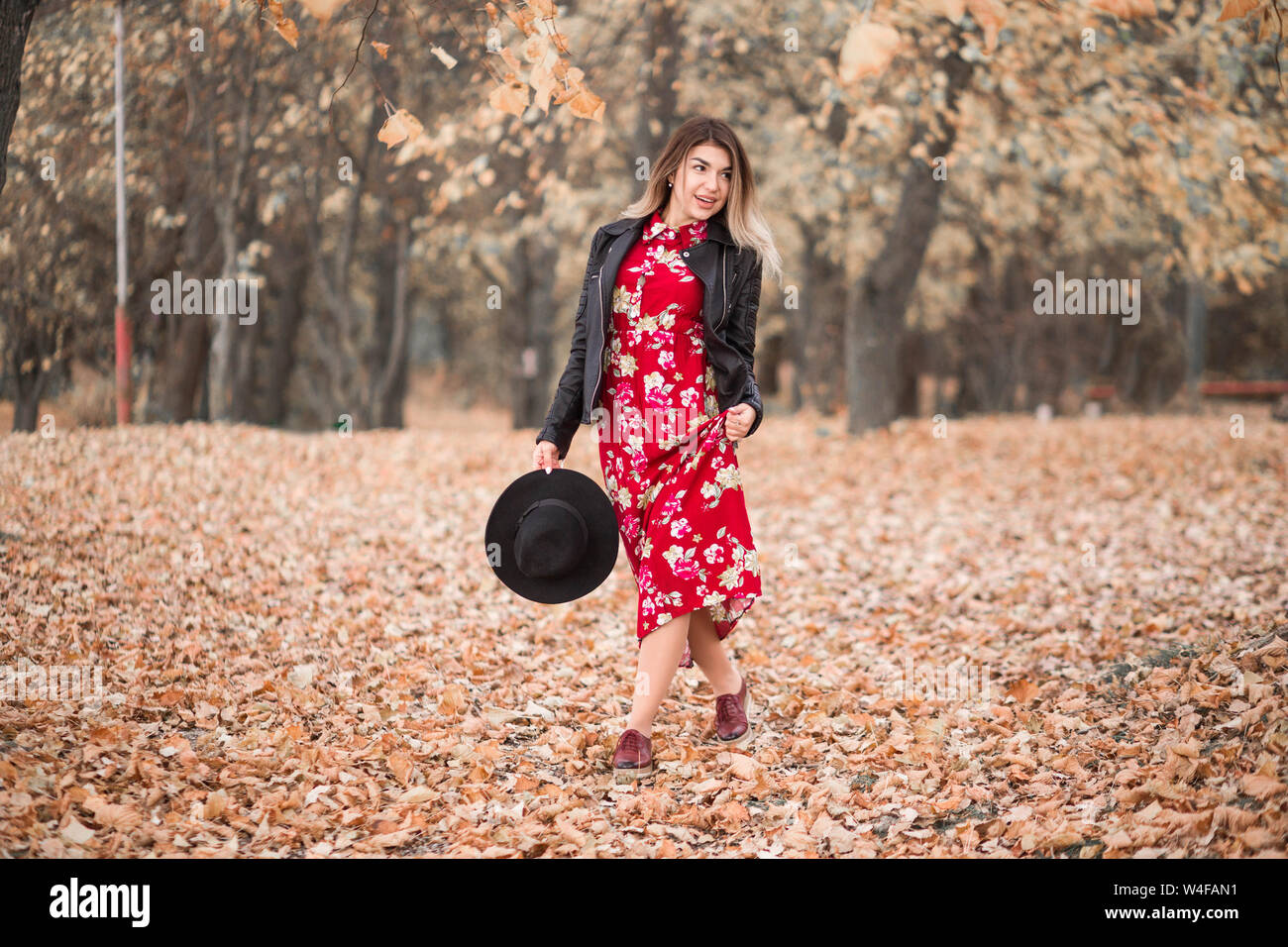 Photo of Beautiful girl in a red dress and black jacket walks in the ...