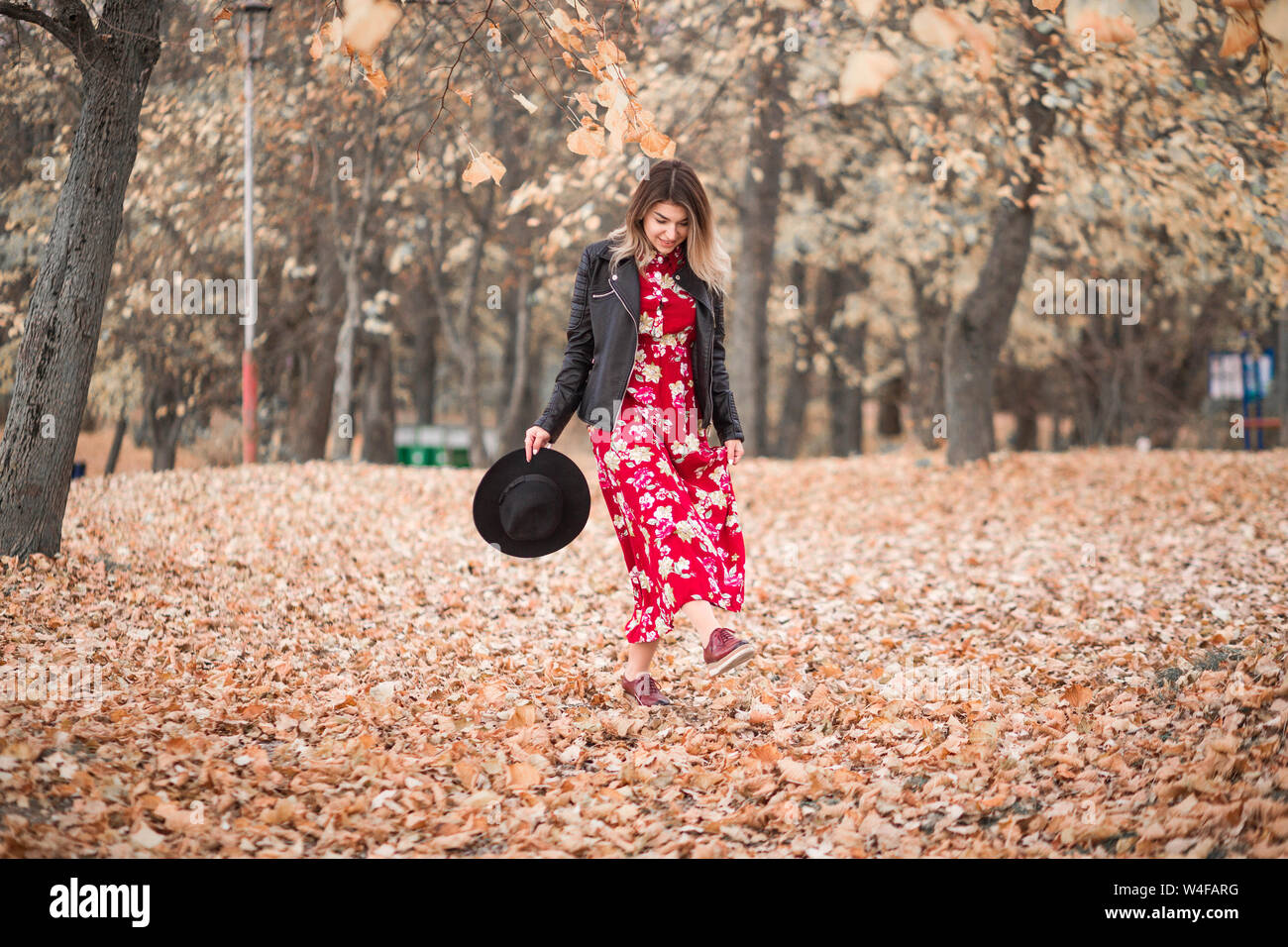 Photo of Beautiful girl in a red dress and black jacket walks in the ...
