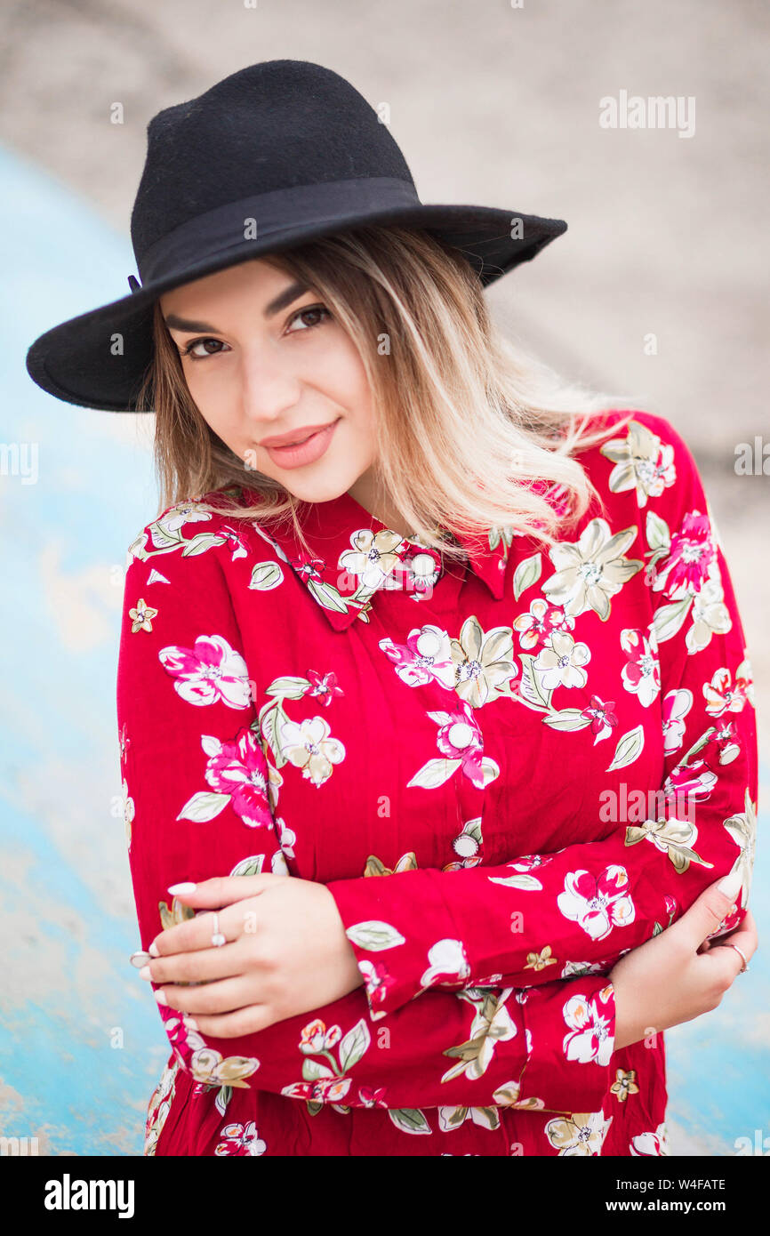 photo of Beautiful girl in red dress and black hat poses for the camera ...