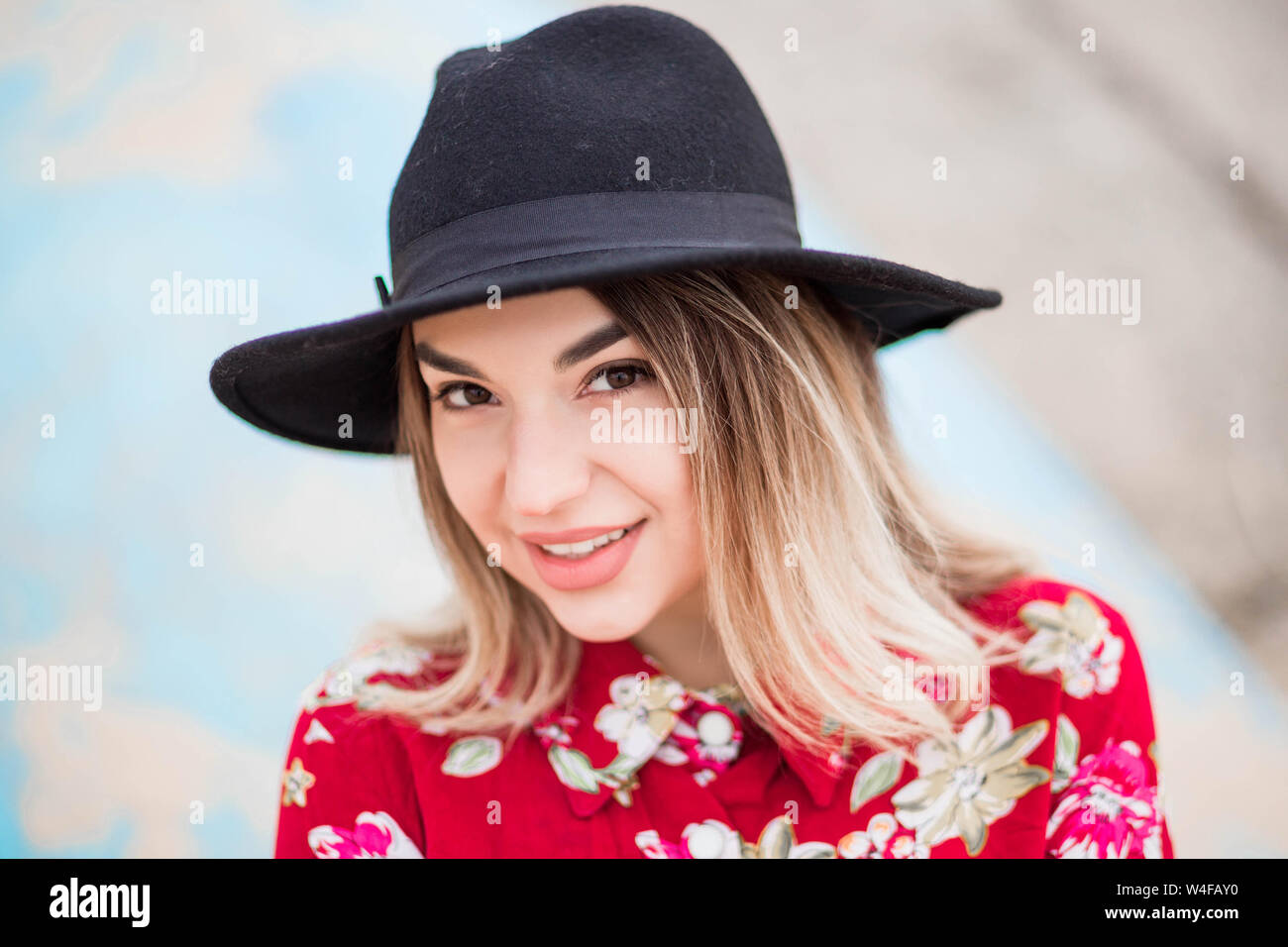 photo of Beautiful girl in red dress and black hat poses for the camera ...