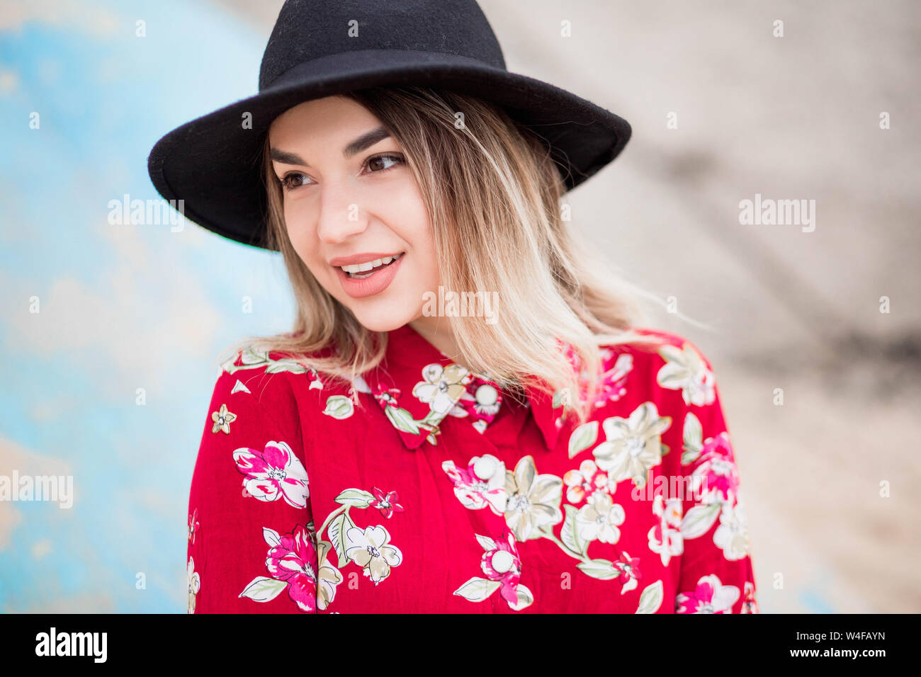 photo of Beautiful girl in red dress and black hat poses for the camera ...