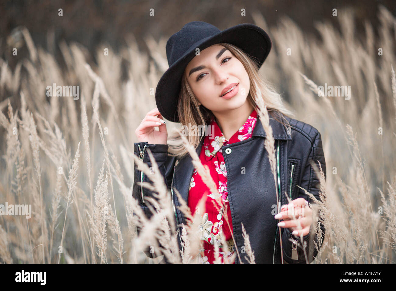 Photo of Beautiful girl in a red dress and black jacket walks among the ...