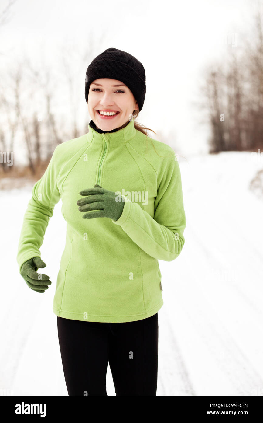Portrait of cheerful woman jogging on winter morning Stock Photo