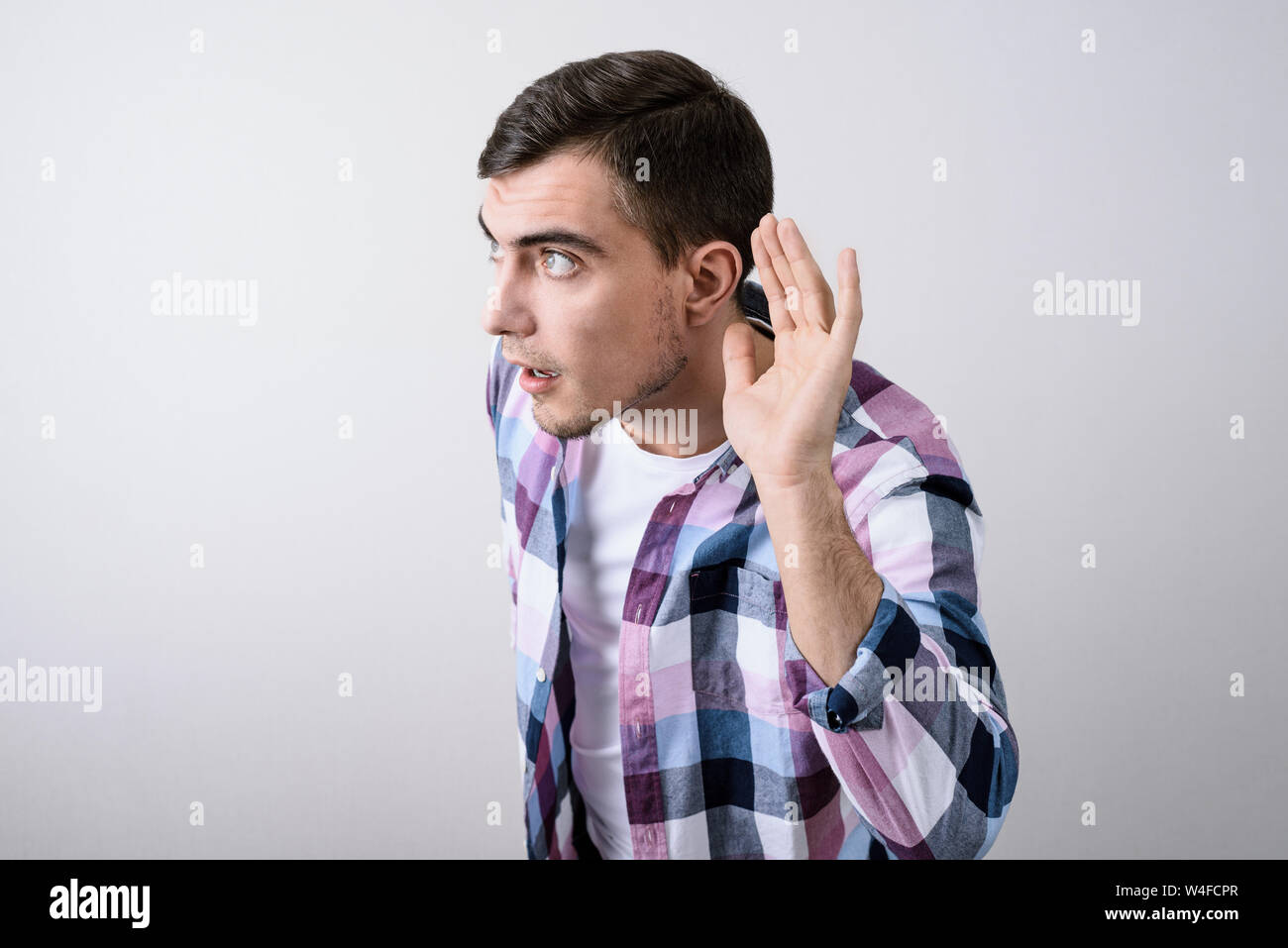 Portrait of close-up of white man holding his hand near his ear ...