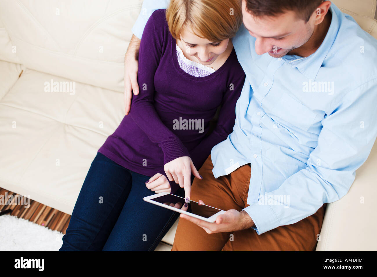 Young hugging  couple sitting on a sofa and using a digital tablet Stock Photo