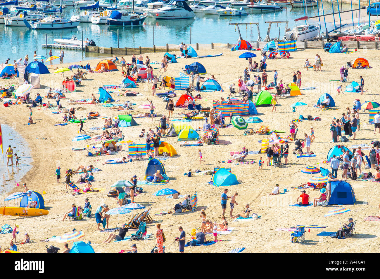 Lyme Regis, Dorset, UK. 23rd July 2019. UK Weather: Sunseekers flock to the picturesque seaside resort of Lyme Regis to soak up the scorching hot sunshine and on the first week of the school summer holidays.  Holidaymakers and families swelter in the hot sunshine on the town's packed beach while others take a cooling dip in the sea on what is set to be the hottest week of the year so far as the African Plume hits southern Britain. Credit: Celia McMahon/Alamy Live News. Stock Photo