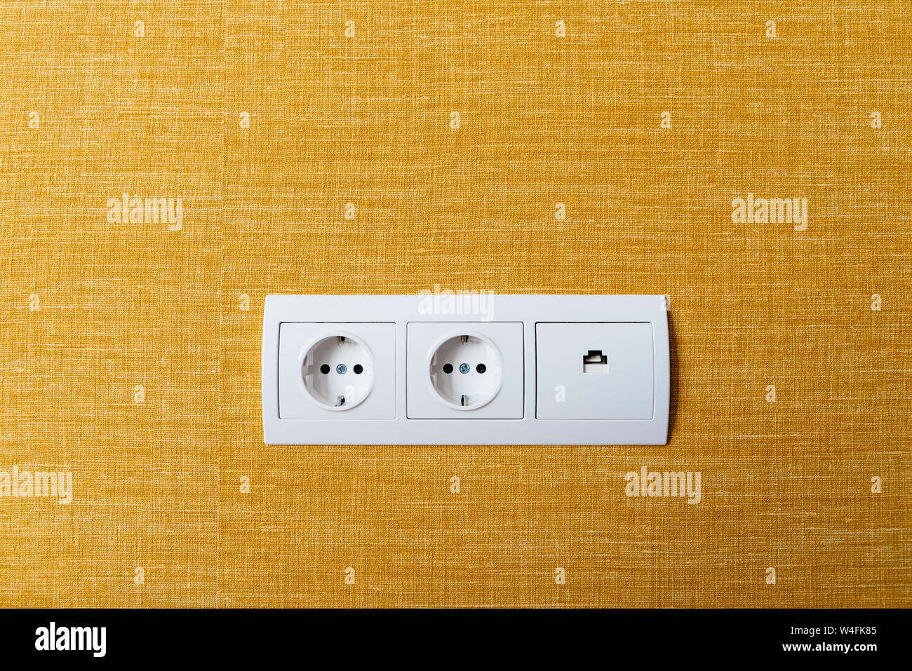White double socket and ethernet plug on yellow wall Stock Photo