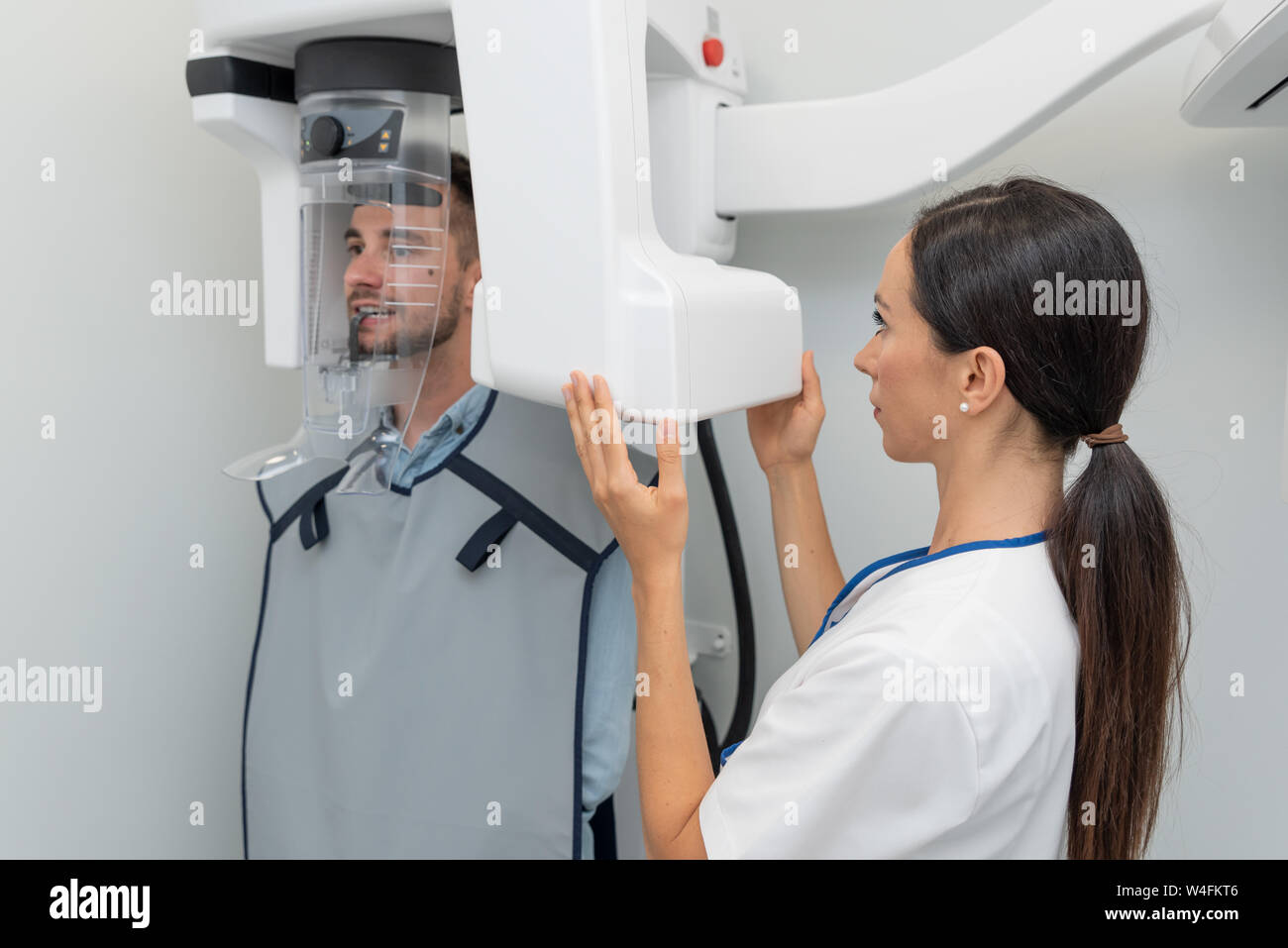 Handsome man patient standing in x-ray machine. Panoramic radiography at professional dental clinic. Stock Photo
