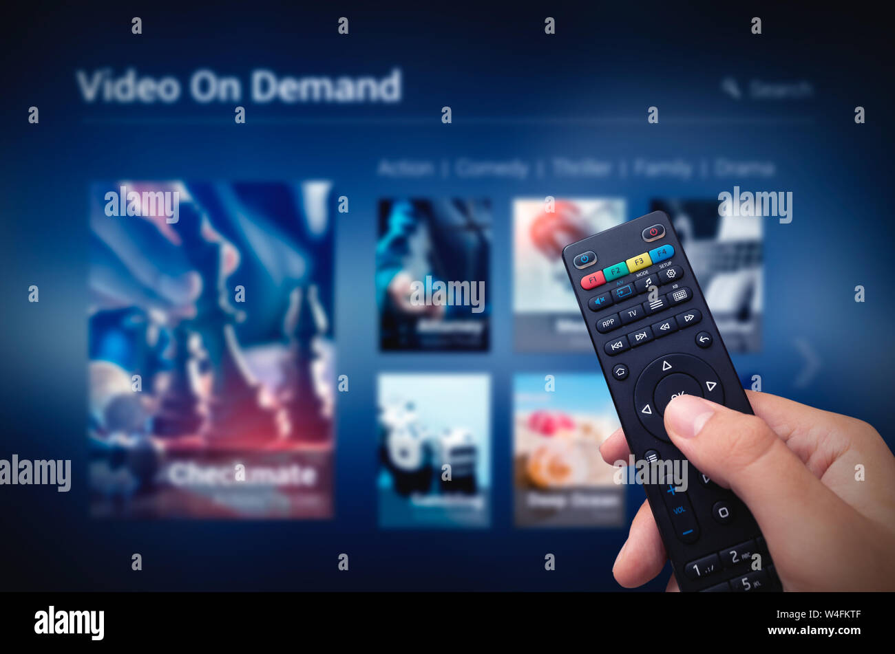 VOD service screen with remote control in hand. Video On Demand television internet stream multimedia concept Stock Photo