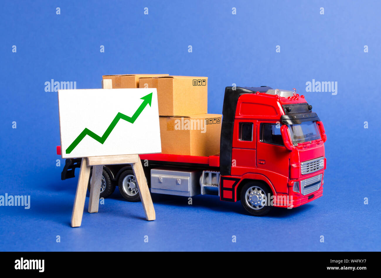 Red truck loaded with boxes and stand with a green up arrow. Raise economic indicators and sales. Exports, imports. High trade volumes, growth product Stock Photo