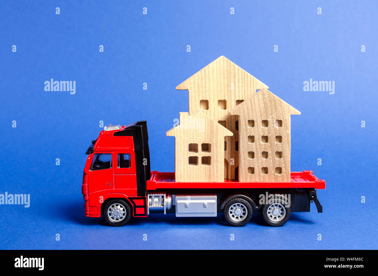 Red truck transports wooden houses. Concept of transportation and cargo shipping, moving company. Construction of new houses and objects. Industry. Lo Stock Photo