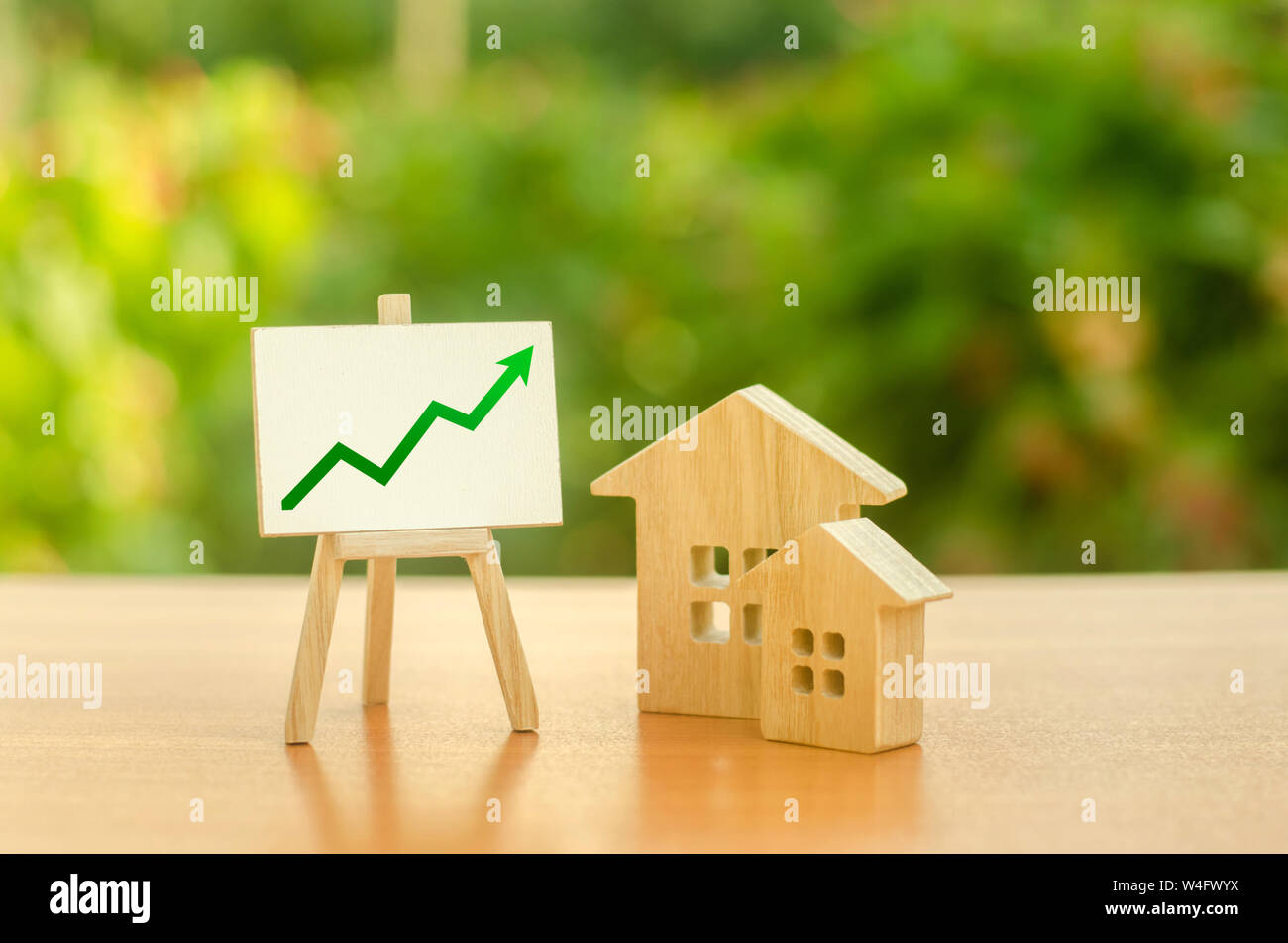 Two wooden houses and stand with green up arrow. Increasing cost and liquidity of real estate. Attractive investing. rising prices or renting. Apartme Stock Photo