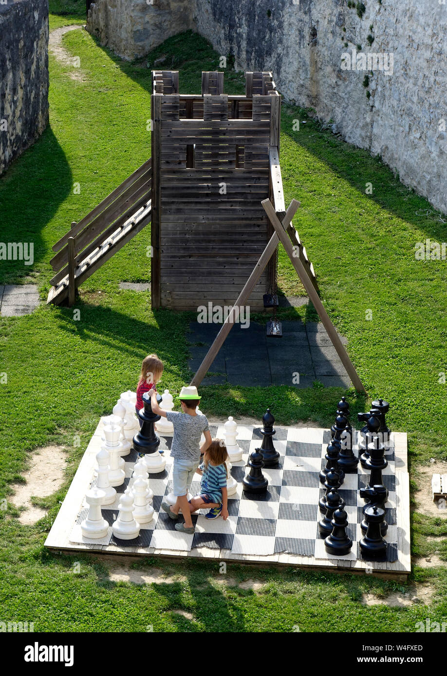 Children play chess in public with large garden chess set.  Celje old Castle. Slovenia Stock Photo