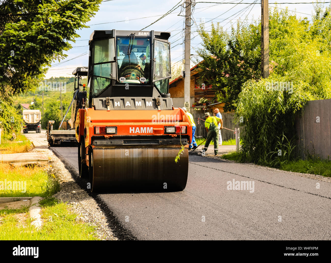 Targoviste, Romania - 2019. Close up photo of an orange road roller  compacting the new asphalt with a dump truck and an asphalt paver in the  backgroun Stock Photo - Alamy