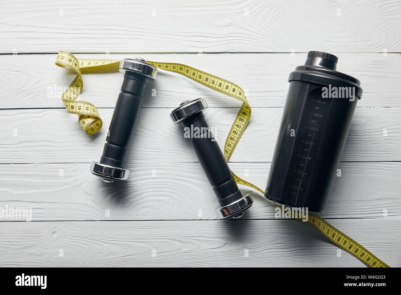 Download Top View Of Black Shaker Cup Yellow Measuring Tape And Dumbbells On Wooden White Background Stock Photo Alamy Yellowimages Mockups
