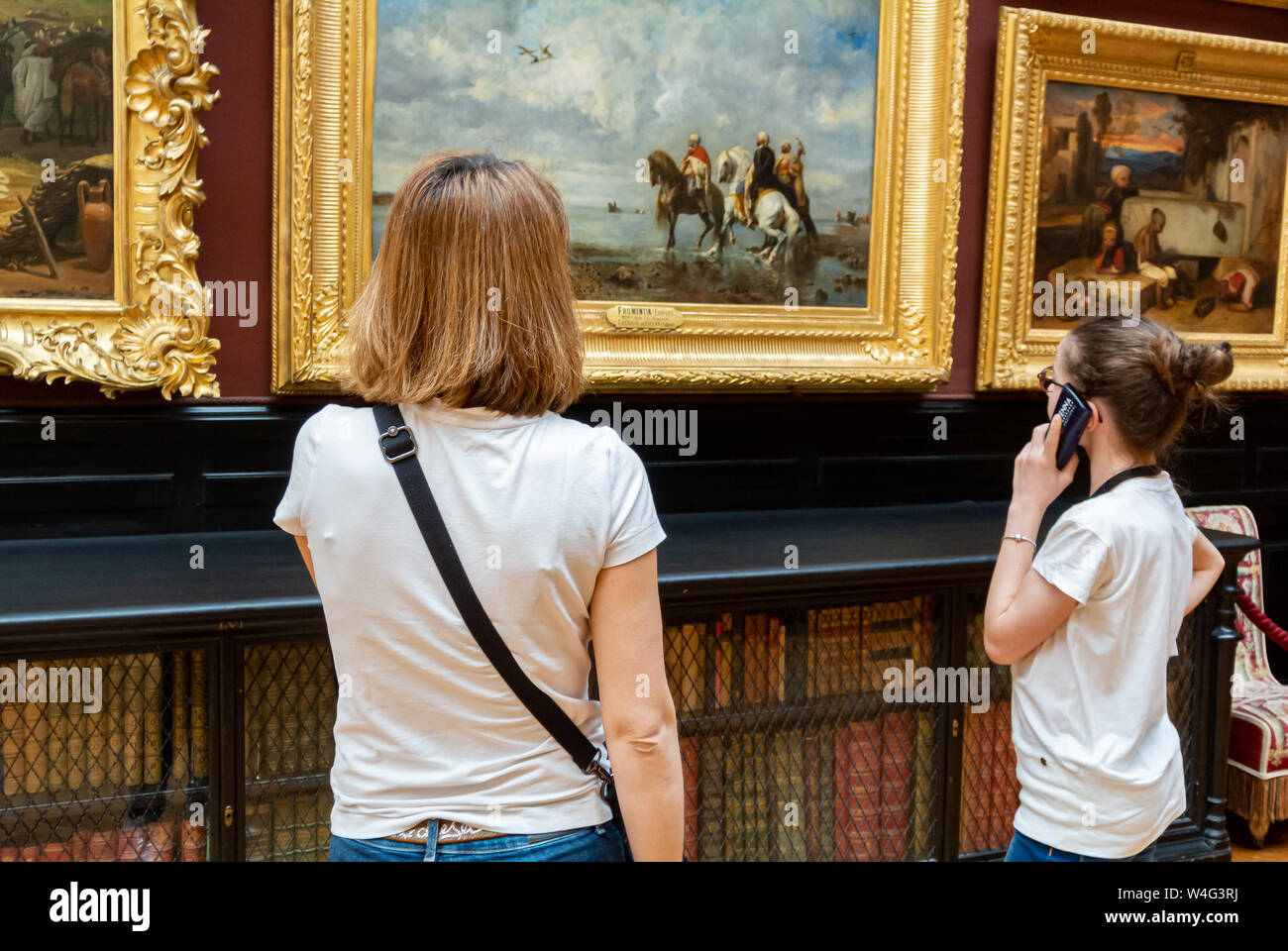 Caucasian Mother and daughter looking at classic oil paintings at conde museum in Chantilly Castle, Chantilly, France Stock Photo