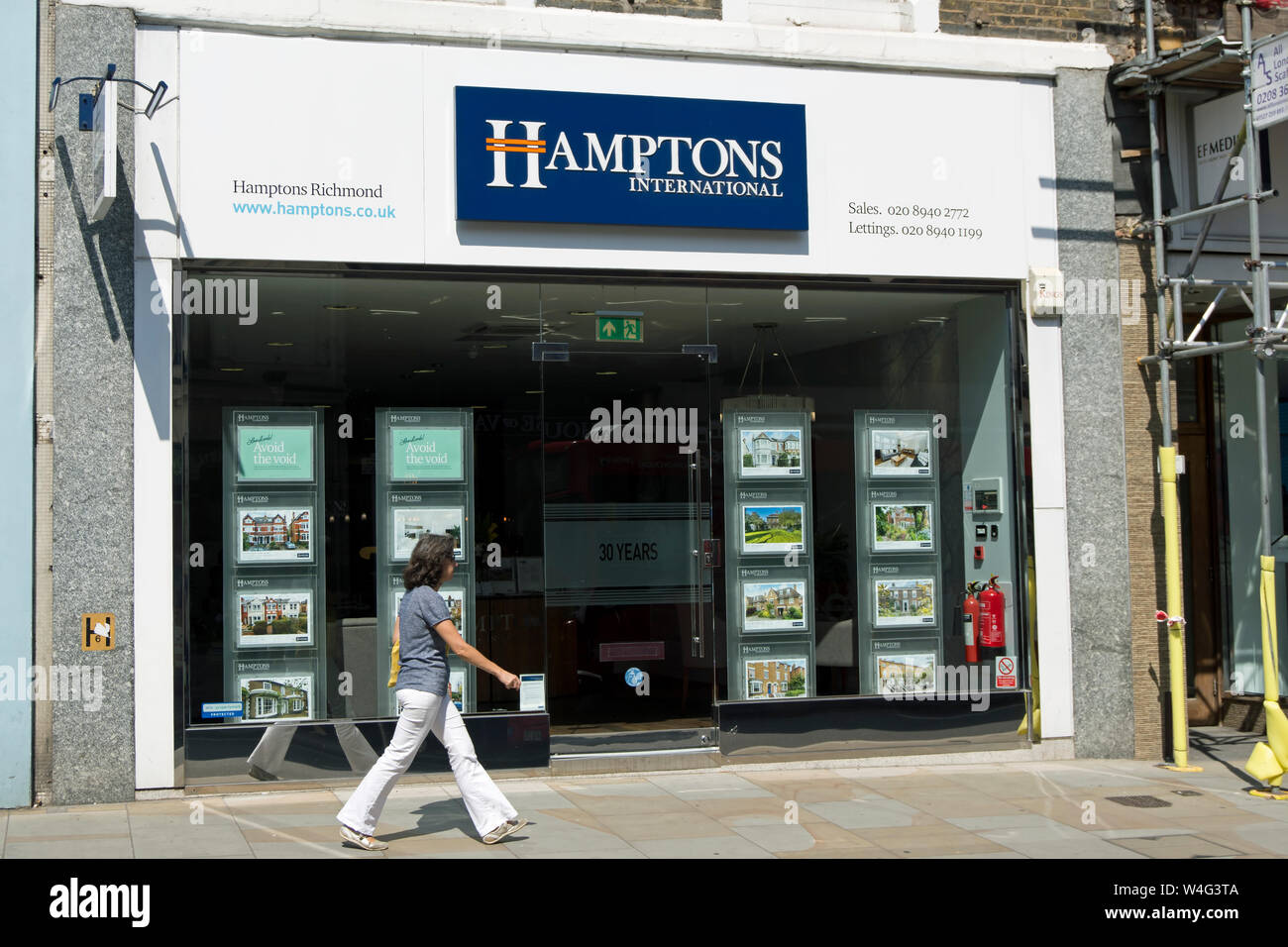 a woman passes a branch of the estate agents hamptons international, in