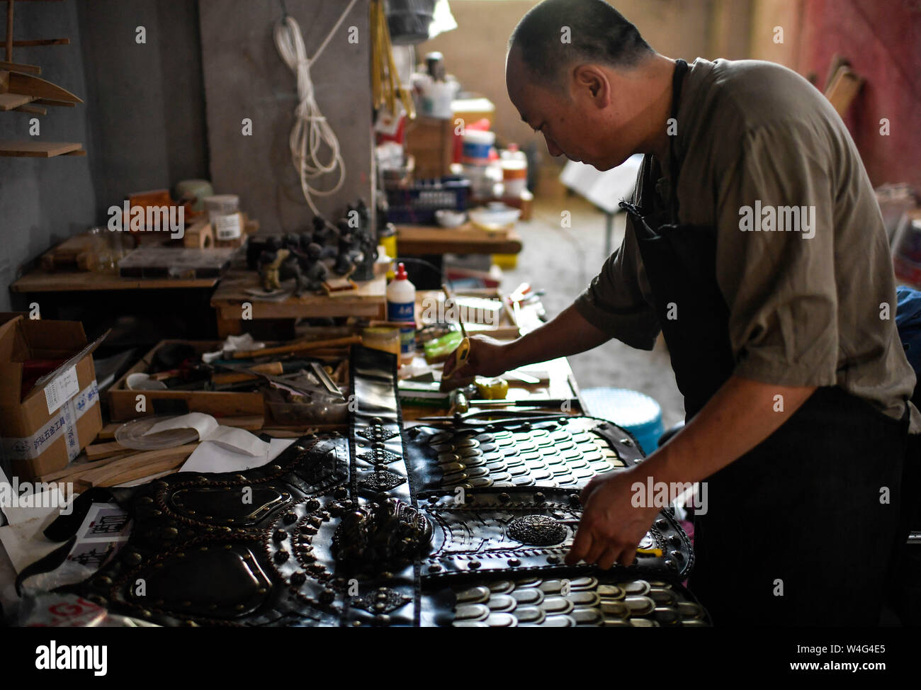 (190723) -- CHANGCHUN, July 23, 2019 (Xinhua) -- Yang Guangquan makes an armor at his studio in Changchun, capital of northeast China's Jilin Province, July 22, 2019. Yang Guangquan, a 50-year-old artisan obsessed with handicrafts, learned forging iron when he was young. He decided to make metal handicrafts in 2013, with application of old blacksmith techniques to make new creations.    After several years of running his studio, Yang has gained customer's affection for his works. He also set up a cooperative platform to develop market for handicrafts, and nearly 100 artisans involved in paper Stock Photo