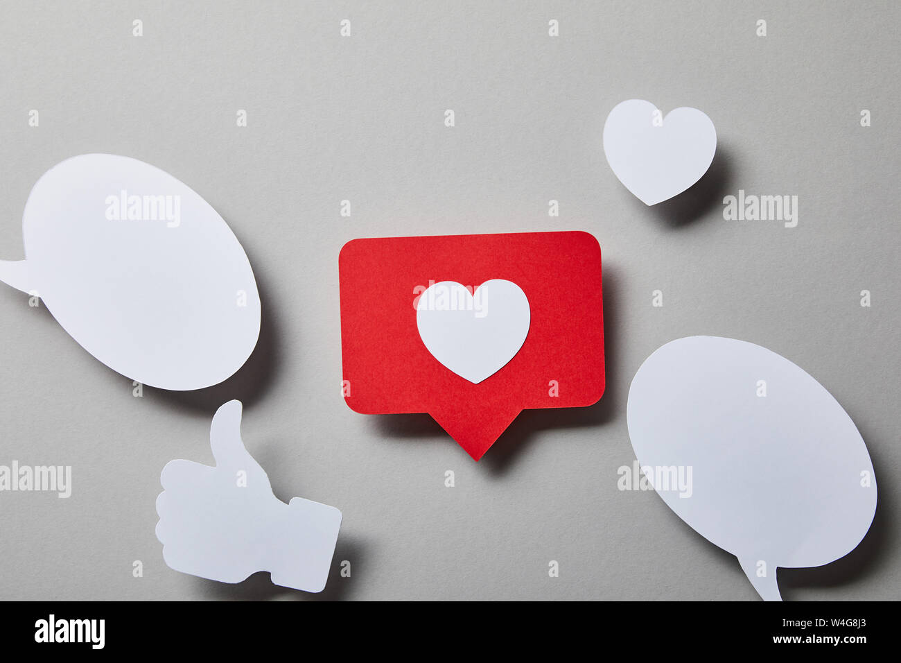 red like card, speech bubbles, thumbs up and small paper heart on white surface Stock Photo