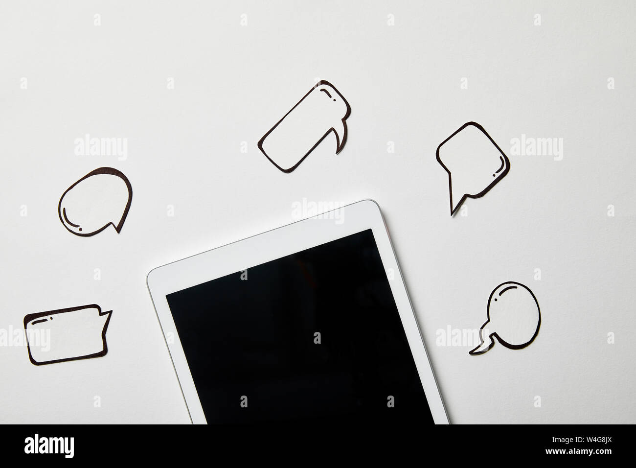 digital tablet with paper thought and speech bubbles on white surface Stock Photo