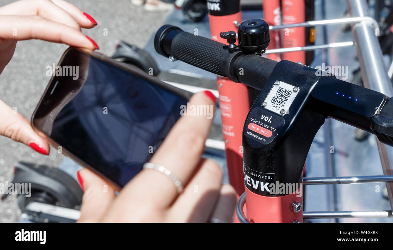 Hamburg, Germany. 23rd July, 2019. A woman unlocks an e- pedal scooter by scanning a QR code. By the end of the year, a pilot project of Hamburger Hochbahn with the Swedish provider VOI will test whether e-scooters are suitable for the first mile as feeder to the underground station. Credit: Markus Scholz/dpa/Alamy Live News Stock Photo