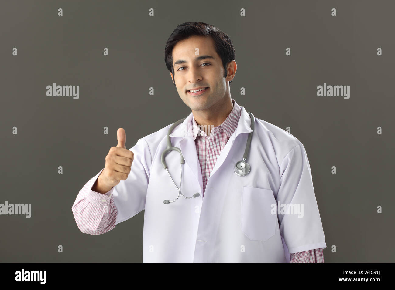 Indian male doctor showing thumbs up sign and smiling Stock Photo - Alamy