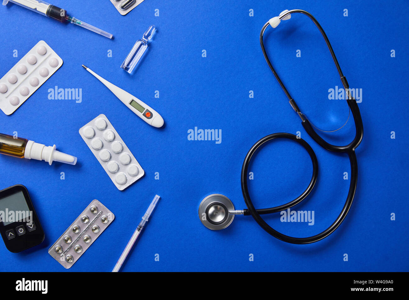 top view of stethoscope near various medical supplies on blue