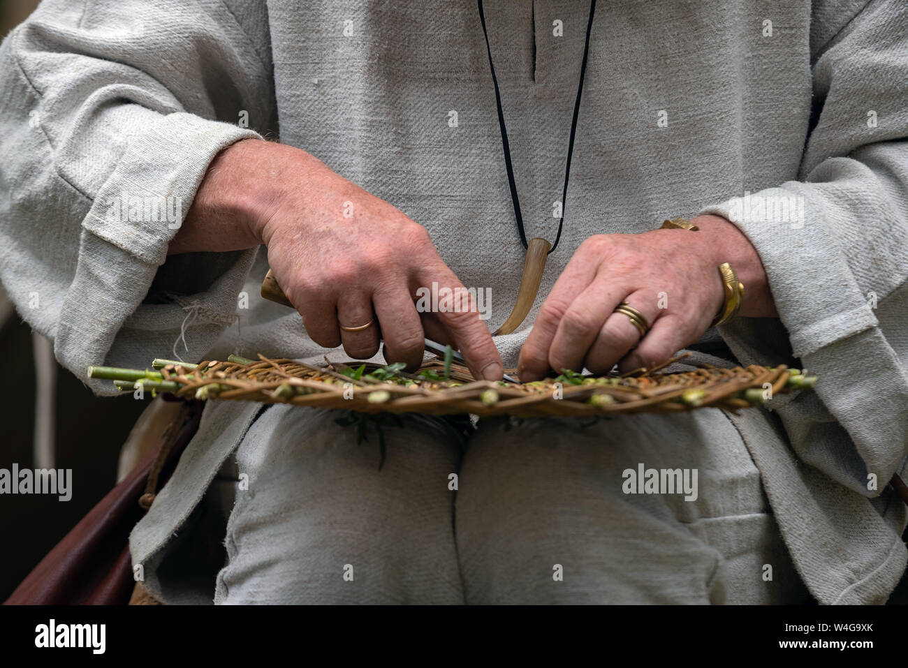 Close up of craftsman wearing rural clothes making wicker basket of
