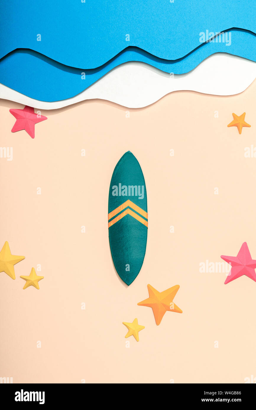 top view of paper beach with surfboard and starfishes on sand near ...