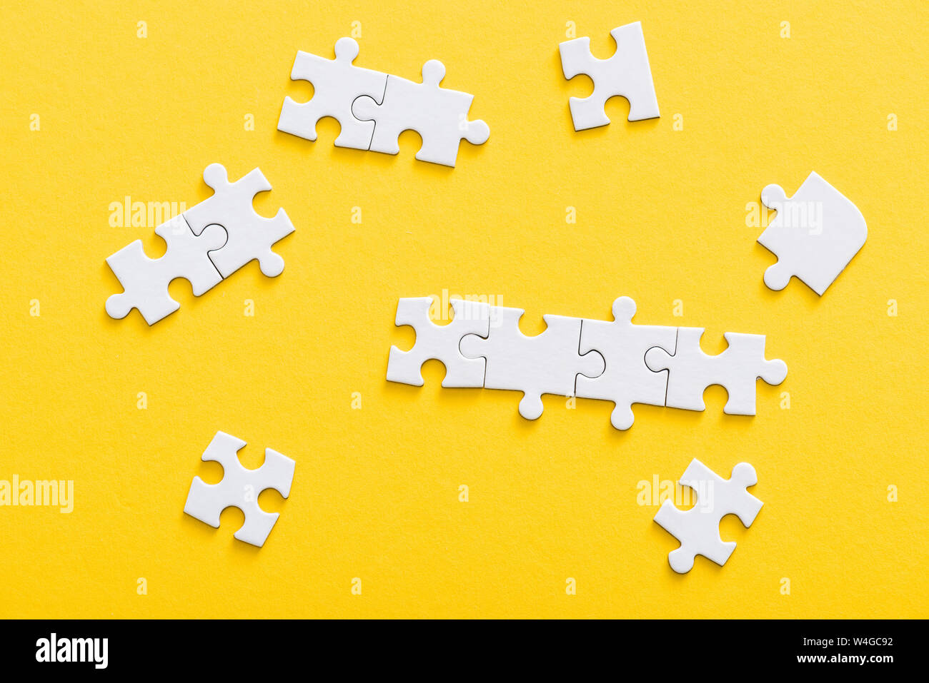 top view of connected jigsaw puzzle pieces isolated on yellow Stock Photo